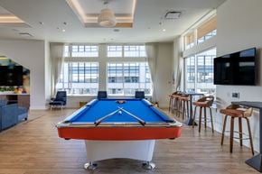 Seattle apartment for rent - A pool table is in the middle of a room with a bar and a television.