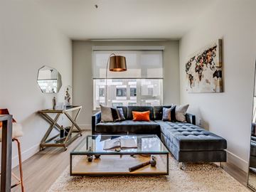 Seattle apartment for rent - A modern living room with a black sofa and a glass coffee table.