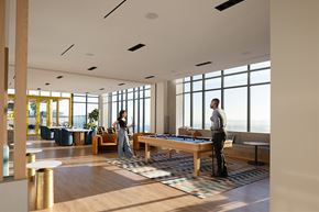 San Diego apartment for rent - Two people playing pool in a brightly lit room with large windows.