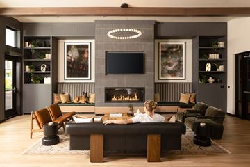 Hillsboro townhouse for rent - A woman is sitting on a couch in a modern living room with a fireplace.