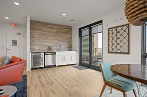 Spartanburg apartment for rent - Aug Smith on Main staged unit with furniture, table, couches, carpet, kitchen, and a balcony.