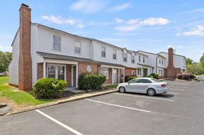 Greenville apartment for rent - A silver car is parked in a parking lot in front of a building.