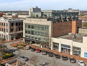 Spartanburg apartment for rent - Overhead view of exterior of Aug Smith on Main, apartments in downtown Spartanburg. The building is a renovated factory in the middle of other stores on the strip.