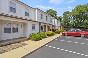 Greenville apartment for rent - A red car is parked in a parking lot in front of a white building.