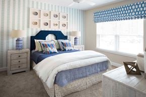 Simpsonville apartment for rent - A bedroom with a bed, nightstands, and a window with a blue and white striped valance.