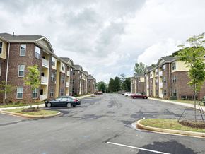 Easley apartment for rent - Creekside Village Apartments Exterior, with two buildings facing each other across a large parking lot and a few cars.