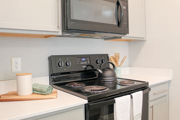 Spartanburg apartment for rent - A modern kitchen with a stove top oven and microwave above it.