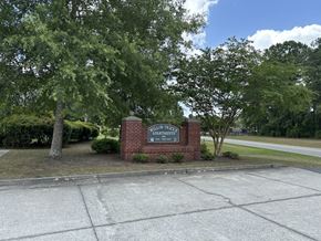 North Charleston apartment for rent - a sign on a brick wall in front of some trees