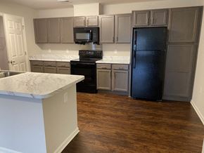 Gastonia apartment for rent - A kitchen with a black refrigerator and white countertops.