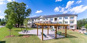 Greenville apartment for rent - A large building with a white and grey exterior and a wooden pergola in front.