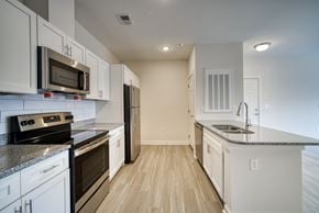 Charlotte apartment for rent - A kitchen with white cabinets and black appliances.