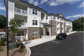 Greenville apartment for rent - A black car is parked in a parking lot in front of a white apartment building.