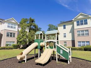 Beaufort apartment for rent - A playground with a green slide and a white railing in front of apartment buildings.