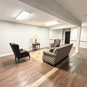 Greenville apartment for rent - A living room with a black chair, a patterned sofa, and a small table with a lamp.