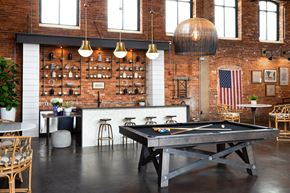 Simpsonville apartment for rent - A pool table is in the middle of a room with a brick wall and a bar area.