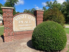 Summerville apartment for rent - a brick sign for western place apartments in front of a bush