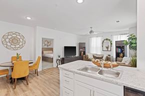 Charlotte townhouse for rent - Ovata at Reedy Creek kitchen and connected living room with modern appliances, a peninsula, white cabinetry and LVT flooring.