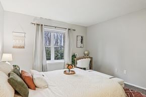 Greenville apartment for rent - Plantations at Haywood staged bedroom with bed, flowers and high window
