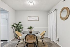 Greenville apartment for rent - Plantations at Haywood living room with table, beige carpet, chairs, and attached kitchen with white appliances
