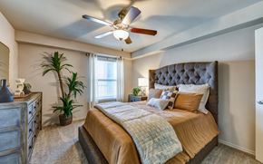 Hewitt apartment for rent - A bedroom with a bed, dresser, and ceiling fan.
