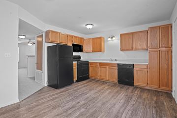Oklahoma City apartment for rent - A kitchen with wooden cabinets and black appliances.