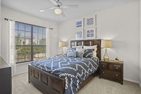 Oklahoma City apartment for rent - A bedroom with a large bed and a ceiling fan.