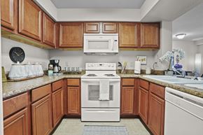 Oklahoma City apartment for rent - A kitchen with wooden cabinets and a white stove top oven.