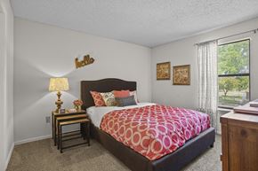 Wichita apartment for rent - A bedroom with a large bed and a lamp on a side table.