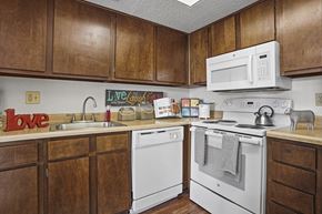 Oklahoma City apartment for rent - A kitchen with wooden cabinets and white appliances.