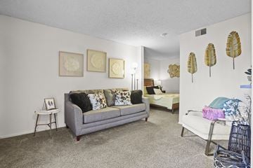 Wichita apartment for rent - A living room with a grey couch and a white chair.