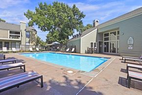 Wichita apartment for rent - A pool area with a bench and a building in the background.