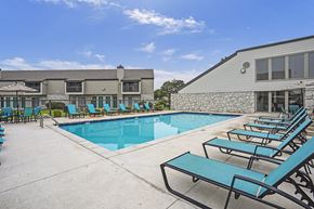 Wichita apartment for rent - A pool area with sun loungers and a building in the background.