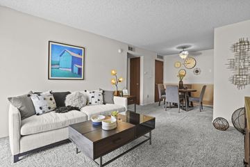 Wichita apartment for rent - A living room with a couch, coffee table, and a painting of a house on the wall.
