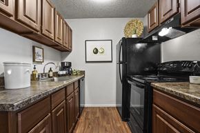 Wichita apartment for rent - A kitchen with brown cabinets and a black refrigerator.