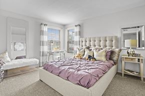 Wichita apartment for rent - A bedroom with a bed covered in a purple comforter and a white headboard.