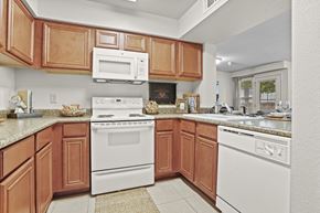 Wichita apartment for rent - A kitchen with brown cabinets and white appliances.