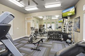 Wichita apartment for rent - A gym with a variety of equipment including treadmills, weights, and a television.
