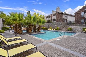 El Paso apartment for rent - A pool surrounded by yellow sun loungers and palm trees.