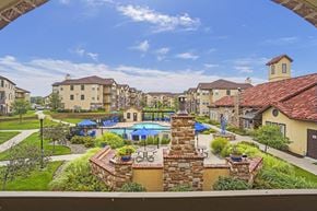 Wichita apartment for rent - A view of a residential area with a pool and a stone wall.