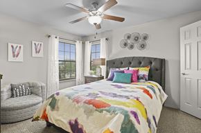 Wichita apartment for rent - A bedroom with a large bed and a ceiling fan.