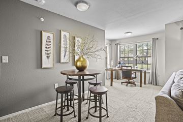 Wichita apartment for rent - A living room with a grey wall and a round table with a gold vase on it.