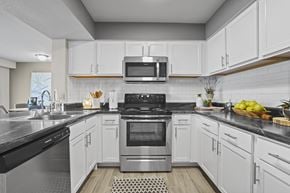 Wichita townhouse for rent - A modern kitchen with white cabinets and stainless steel appliances.