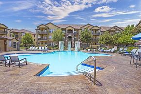 Amarillo apartment for rent - A large swimming pool surrounded by lounge chairs in front of apartment buildings.