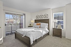 El Paso apartment for rent - A bedroom with a bed, nightstand, and a window with a view of a parking lot.