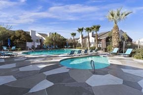 El Paso apartment for rent - A pool surrounded by palm trees and lounge chairs.