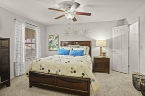 Lubbock apartment for rent - A bedroom with a large bed and a ceiling fan.