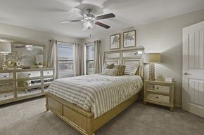 Lubbock apartment for rent - A bedroom with a large bed and a ceiling fan.