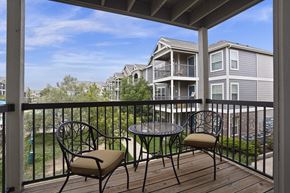 Lubbock apartment for rent - A balcony with a table and two chairs overlooks apartment buildings.