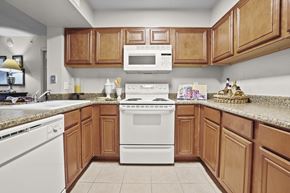 Edmond apartment for rent - A kitchen with brown cabinets and a white stove top oven.