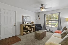 El Paso apartment for rent - A living room with a white door, a grey sofa, and a wooden bookshelf.